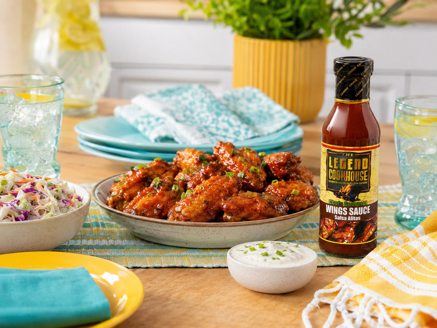 Legend Wings Sauce shown on a colorful home serving table with sauced wings, sides, dip, plates, and a visible bottle.